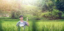 a young man holding a Bible praying in a rice field 