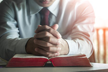 businessman praying over an open Bible 