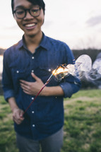 A young man holding a sparkler.