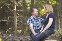Couple sitting together and having a nice conversation while sitting on log