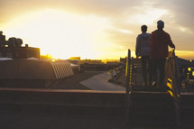 Two young men on rooftop at sunset.