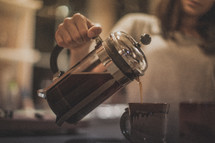 A woman pouring coffee from a French press