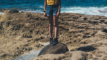 woman standing on a rock on a beach 