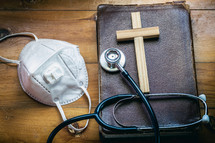 face mask, stethoscope, Bible, and wooden cross 
