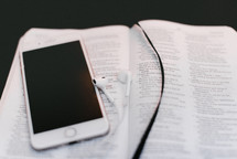 iPhone and earbuds on the pages of a Bible 