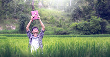 Young man with hands raised standing in a rice field 