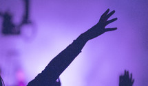 silhouette of a raised hand at concert 