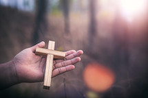 wooden cross in the palm of a hand outdoors 