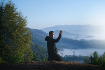 person kneeling in prayer on a mountaintop 
