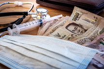 Close up a stethoscope with a surgical mask, injections and Thai money