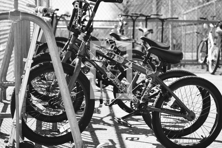 rows of parked children's bicycles on bike racks at a school 