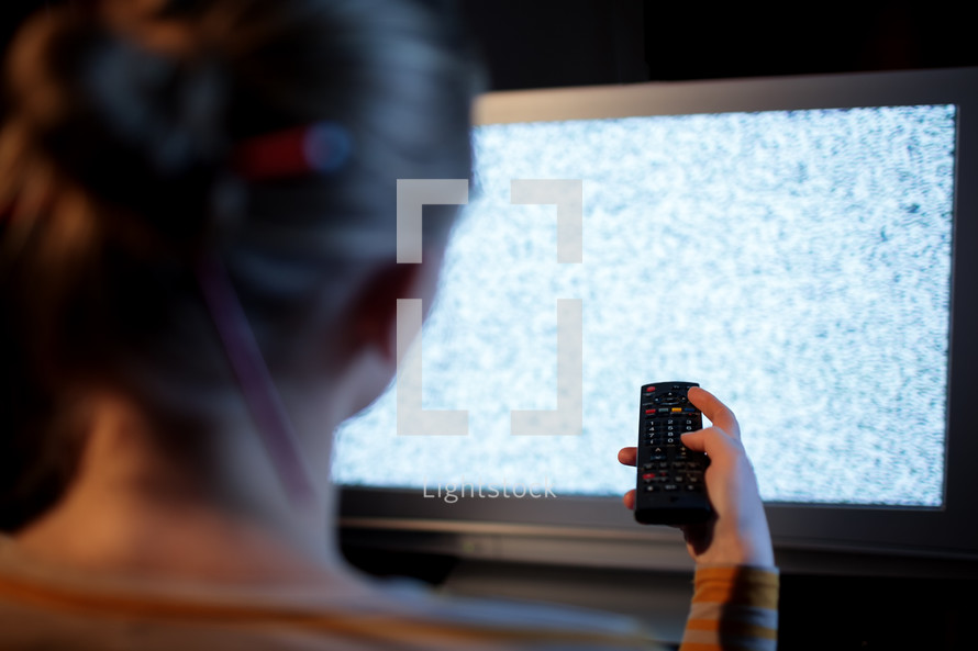 Woman with remote control in front of TV set