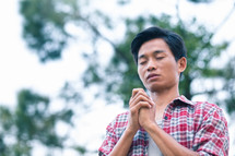 young man praying outdoors 