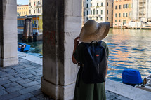 a woman in a sunhat looking out at a chanel in Venice 