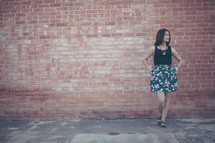 a woman posing in front of a brick wall 