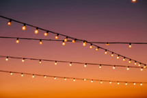 string of lights against an orange sky at sunset 