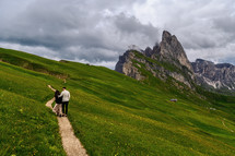 a couple walking on a trail on a mountainside 