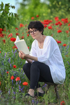 a woman reading in a meadow of poppies 