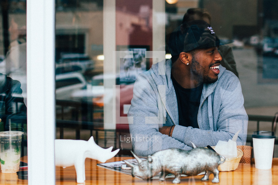 A smiling man sitting in the window of a restaurant.