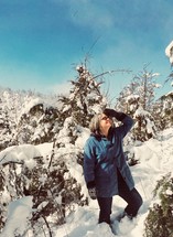 a woman standing outdoors in the snow looking up at the sky 