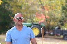 man standing in front of a green tractor 