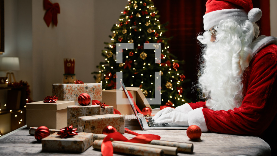 Santa Claus writing on Pc under Christmas tree