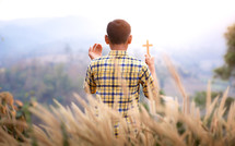 a young man standing in a field with hands raised 