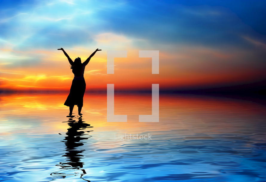 Silhouette of woman standing on water praising God.