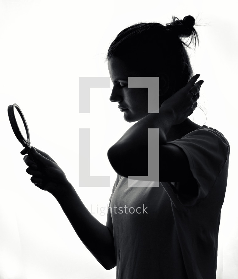 A charming young girl silhouette looking in the mirror 