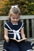 girl in a dress reading a book
