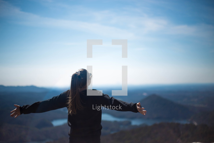 woman standing on a mountaintop with outstretched arms 
