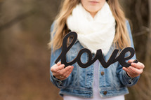 woman holding a sign of the word love 