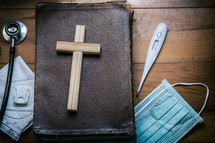 Bible, face mask, wooden cross, and stethoscope 