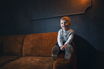 Adorable Handsome Little Cute Boy on Vintage Sofa in Dark Interior