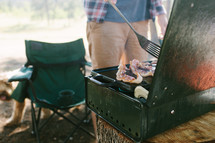 a man flipping bacon on a campsite 