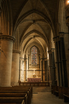 Sunlight shining into Norwich Catholic Cathedral halls, beautiful stained glass window with a cross