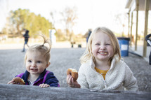 Two little girls eating a donut and smiling