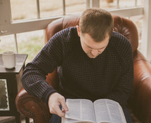Man sitting in a chair reading the Bible.