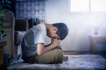 a boy with head bowed praying 