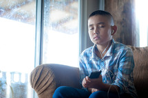a boy holding a cellphone and listening to a sermon from home 