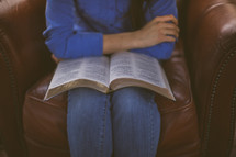 A woman sitting in a chair with an open Bible in her lap