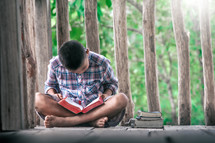 a boy reading a Bible outdoors 