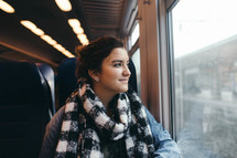a woman riding on a train looking out the window 