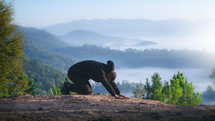 a man kneeling in prayer on a mountaintop 
