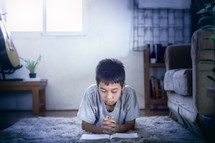 a boy reading a Bible and praying 