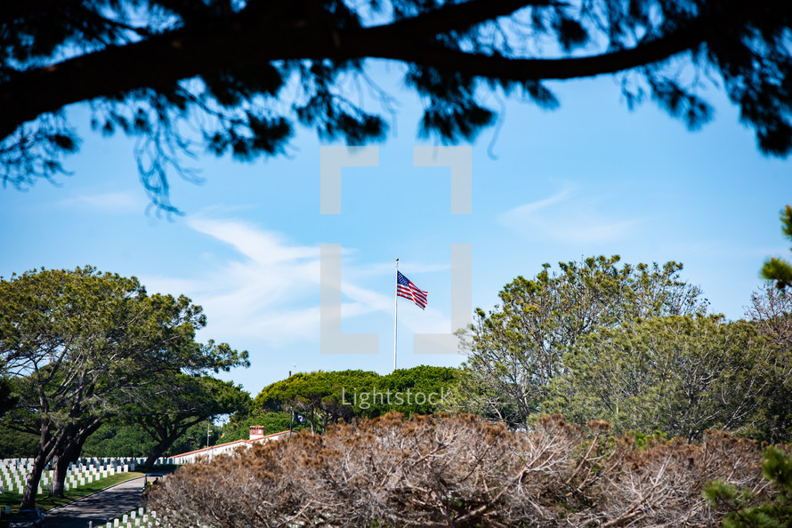 American flag on a flagpole above a cemetery 