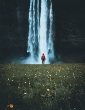 person in a rain jacket standing in front of a waterfall 