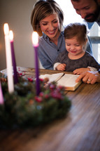 a family reading a Bible in front of an Advent wreath 