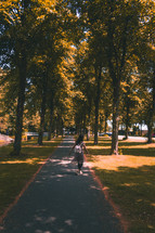 a woman walking on a paved path in a park 