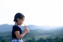 a girl holding a cross praying 